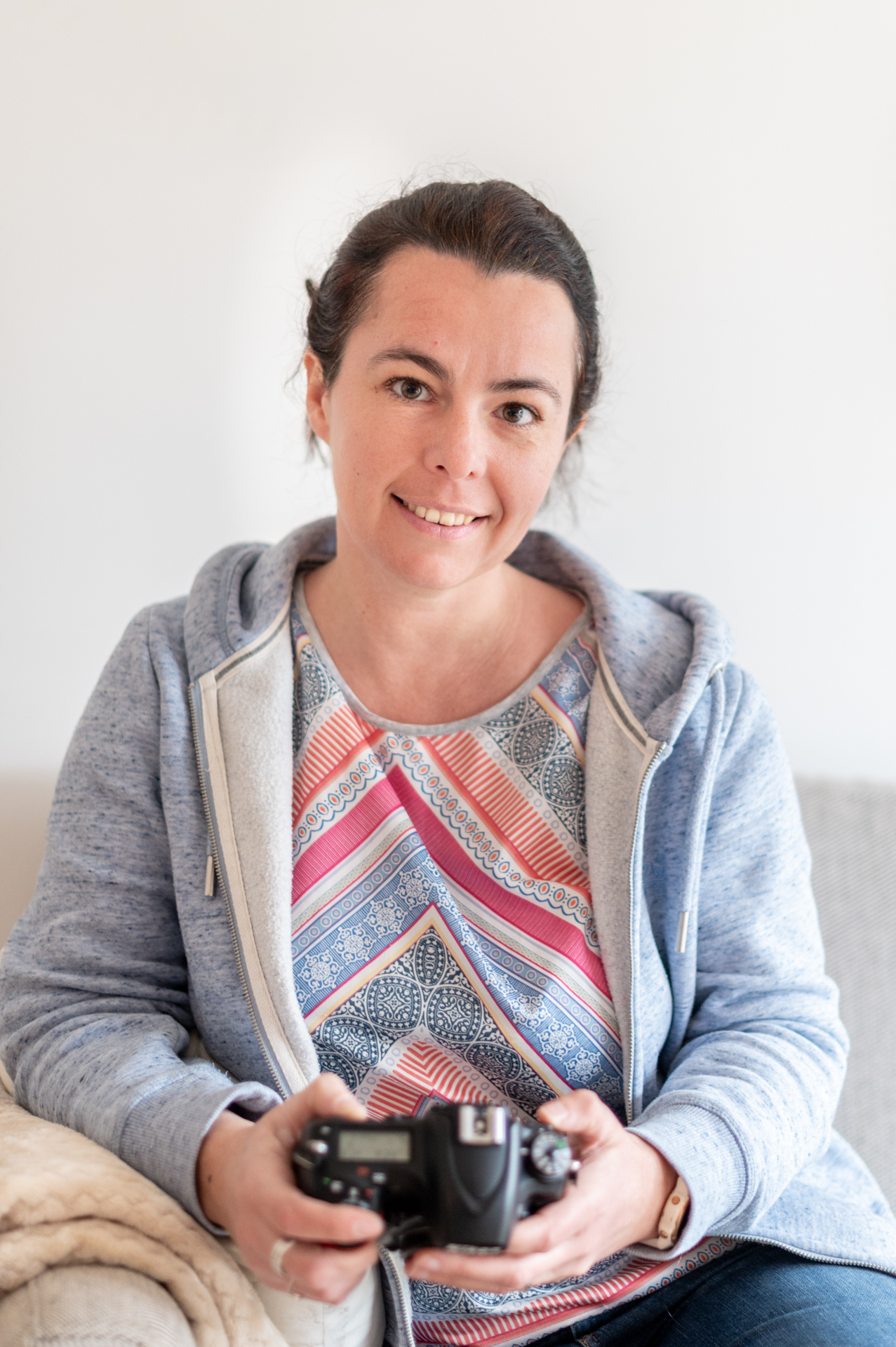 Portrait d'Aurélie Follain, souriante et positive, tenant un appareil photo à la main
