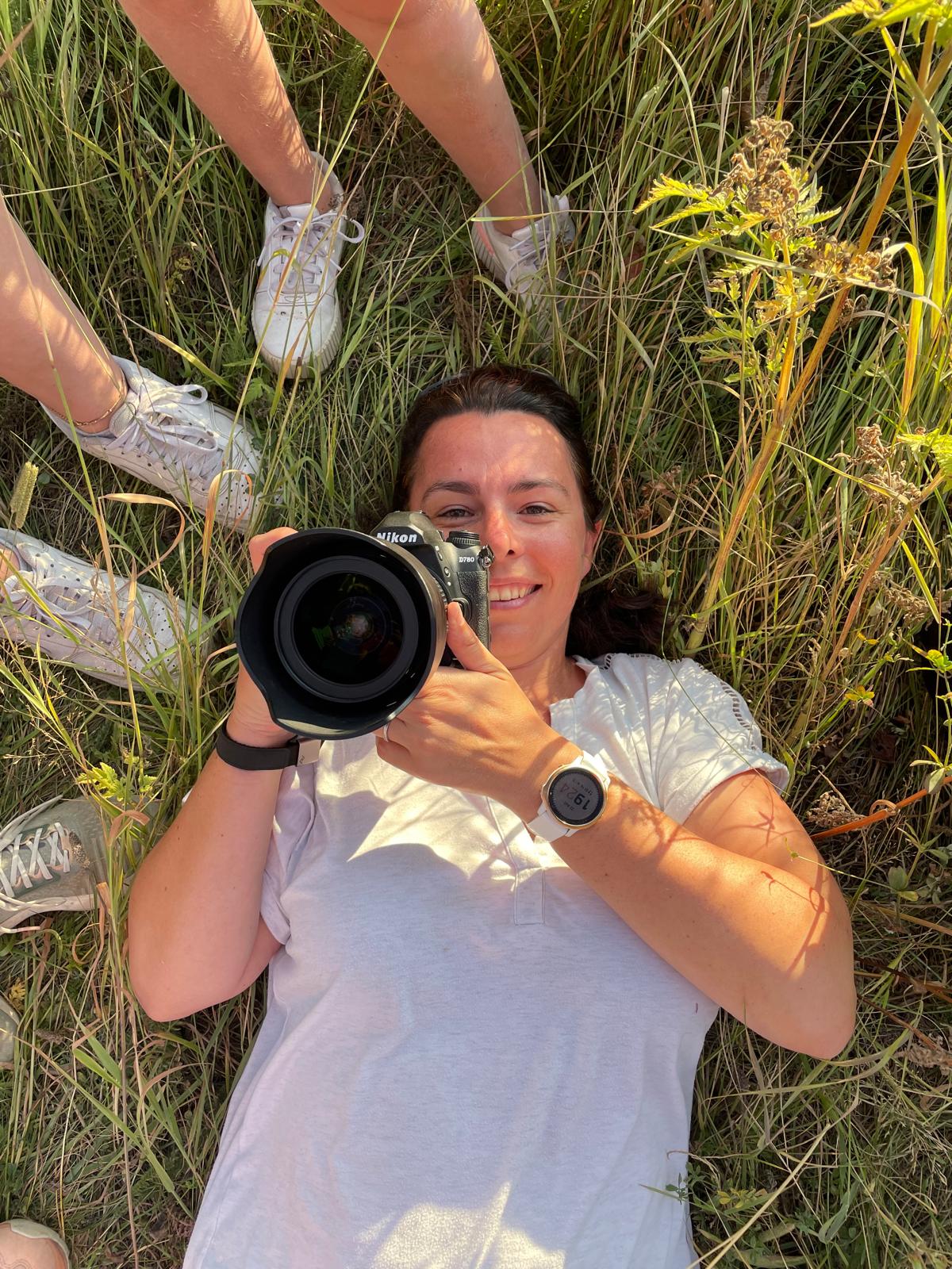 Aurélie Follain, allongée dans l'herbe appareil photo à la main.